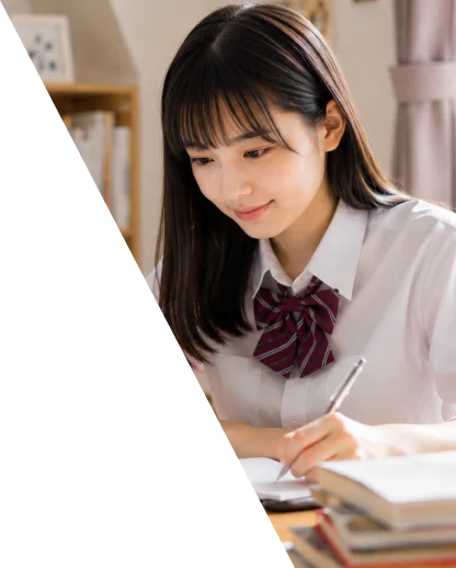 机でノートを広げ、ノートパソコンを見ながら勉強している制服姿の高校生